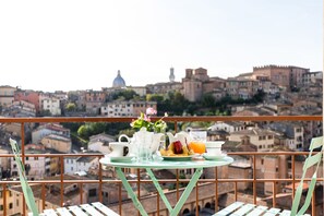 Balcón con mesa listo para el desayuno, con vistas a un paisaje urbano histórico con edificios con cúpulas y casas escalonadas.