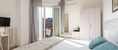 Una habitación de hotel con cama, escritorio, televisor y armario.
