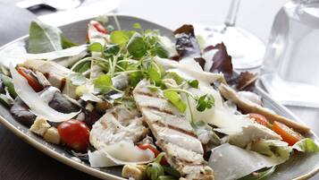 A plate of grilled chicken salad with various greens and vegetables.
