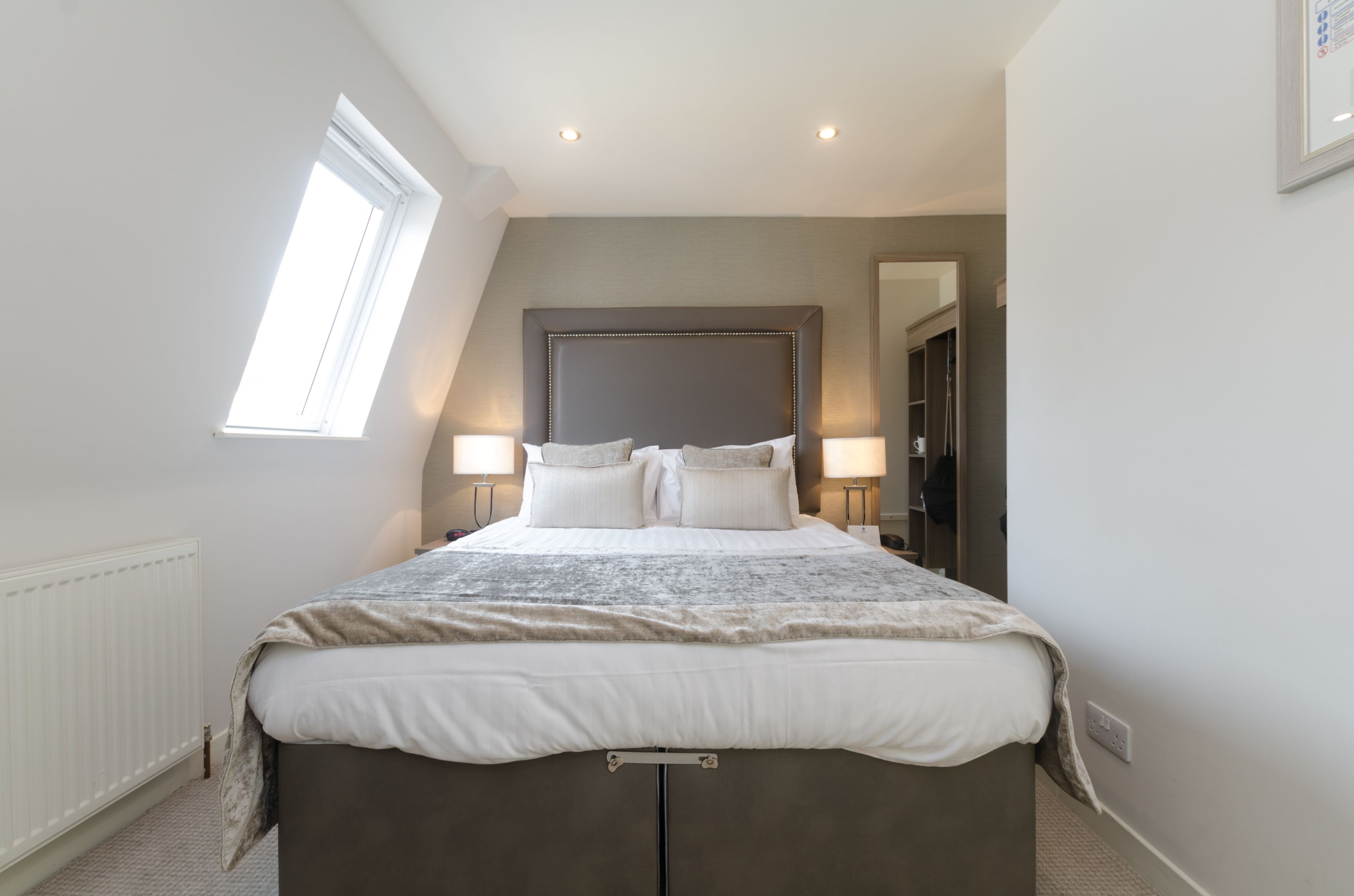 Ein Schlafzimmer mit einem großen Bett, zwei Nachttischlampen, einem Fenster und einem Kleiderschrank.
