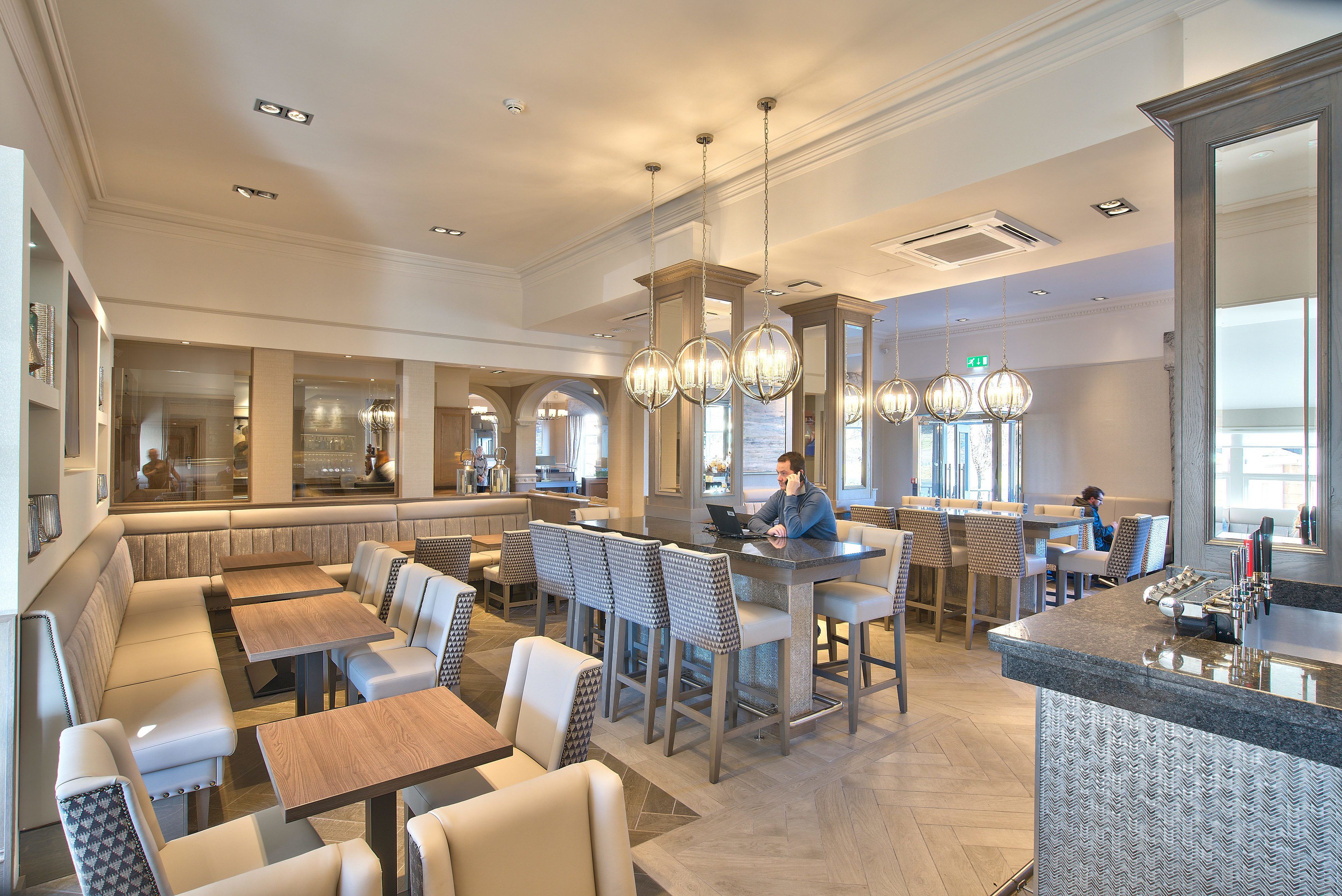 A spacious restaurant with high ceilings, modern lighting, and a mix of seating options including booths and bar stools.