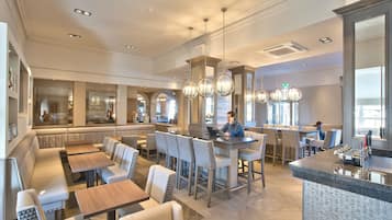 A spacious restaurant with high ceilings, modern lighting, and a mix of seating options including booths and bar stools.