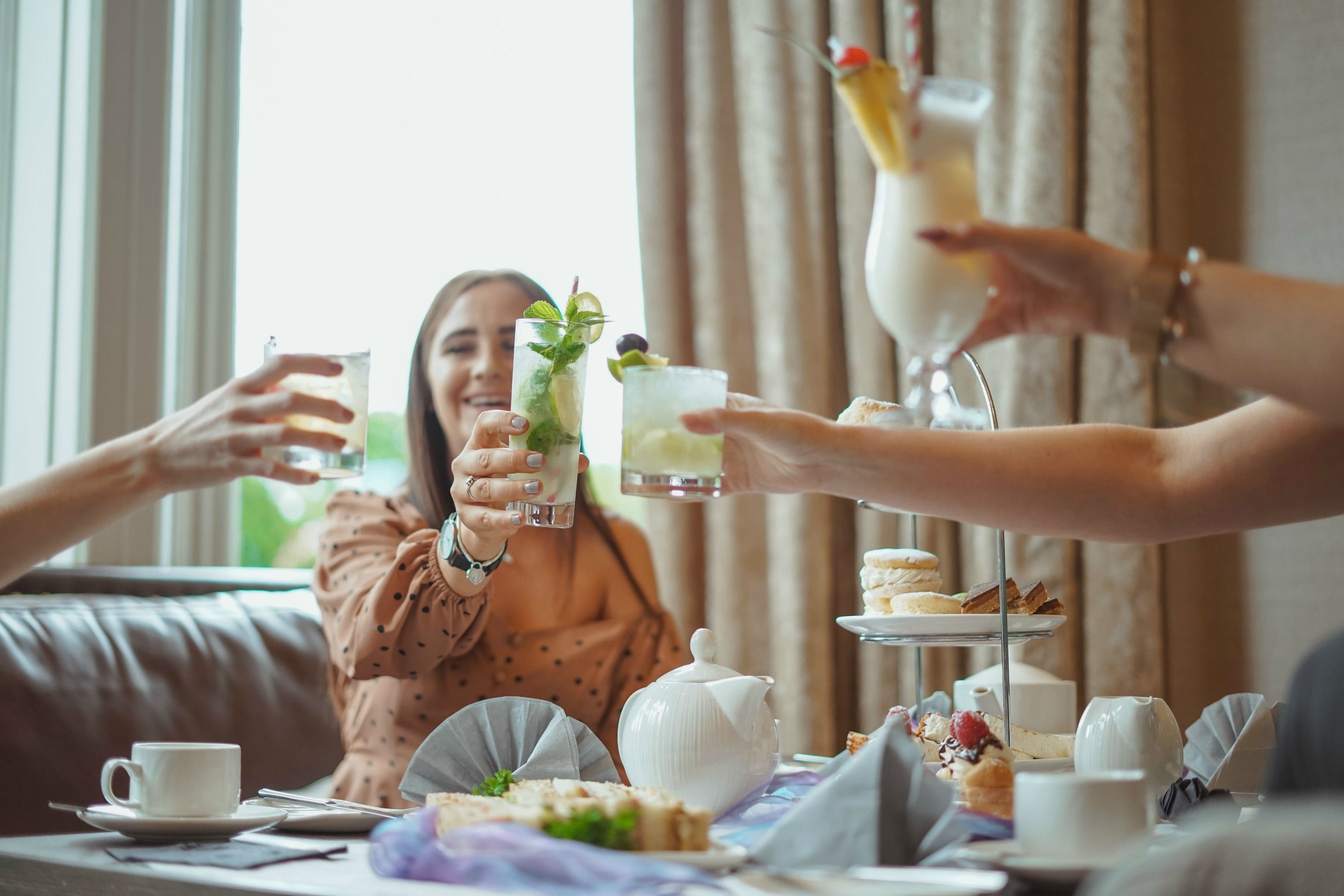 A group of people enjoying a tea time with various pastries and drinks at a table.