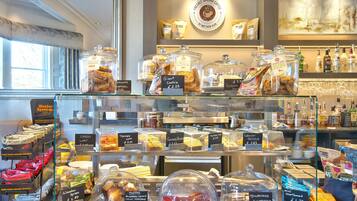 A bakery display with various baked goods and a coffee shop in the background.