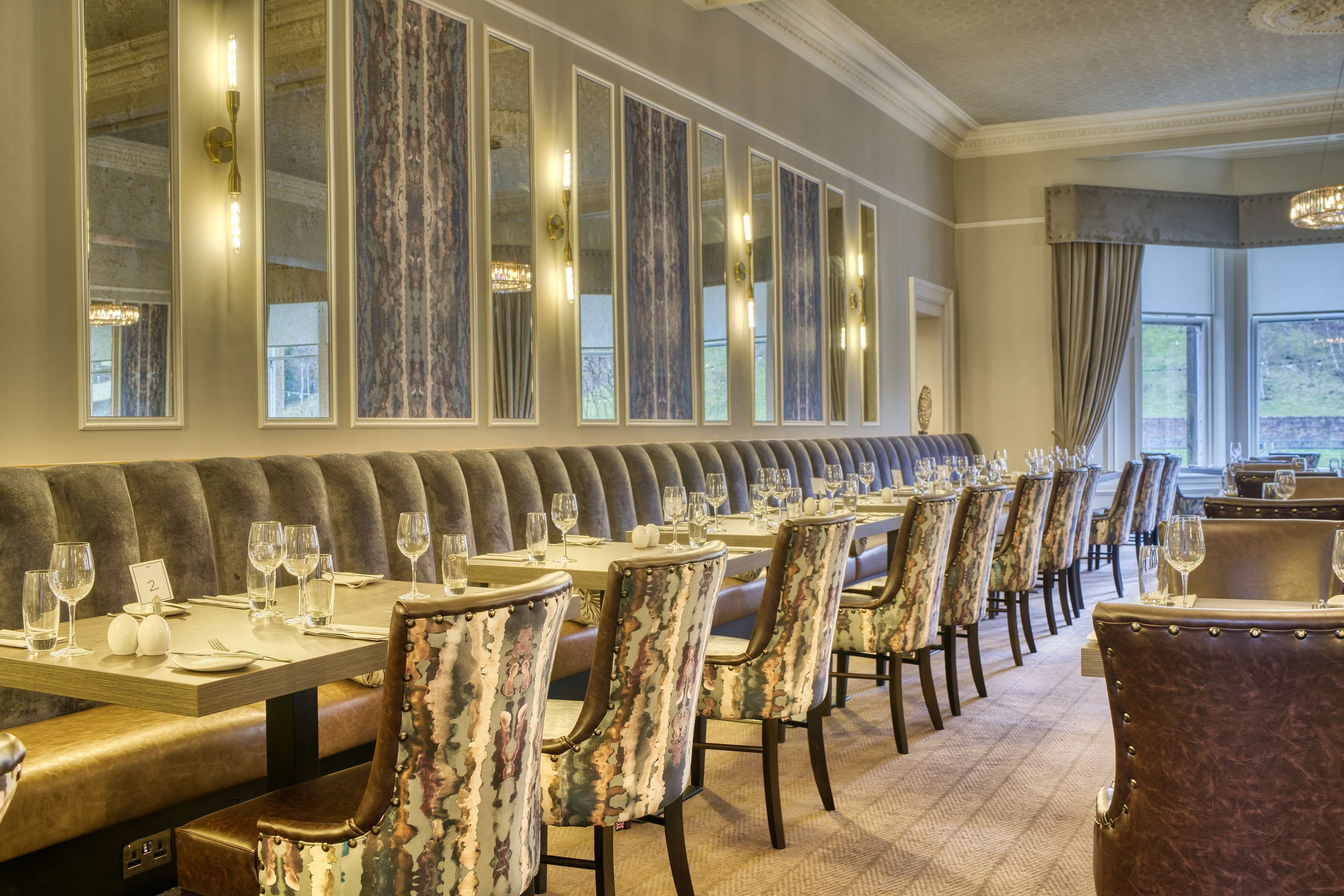 A formal dining area with a long bench, multiple tables, and upholstered chairs.