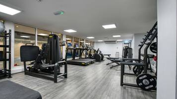 A gym with various exercise equipment, including treadmills, weight machines, and free weights.