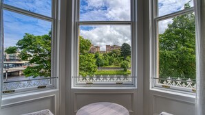 A room with a round table and two chairs, large windows with white frames, and a view of a building and trees. - Inverness Palace Hotel & Spa, WorldHotels Distinctive (Inverness)