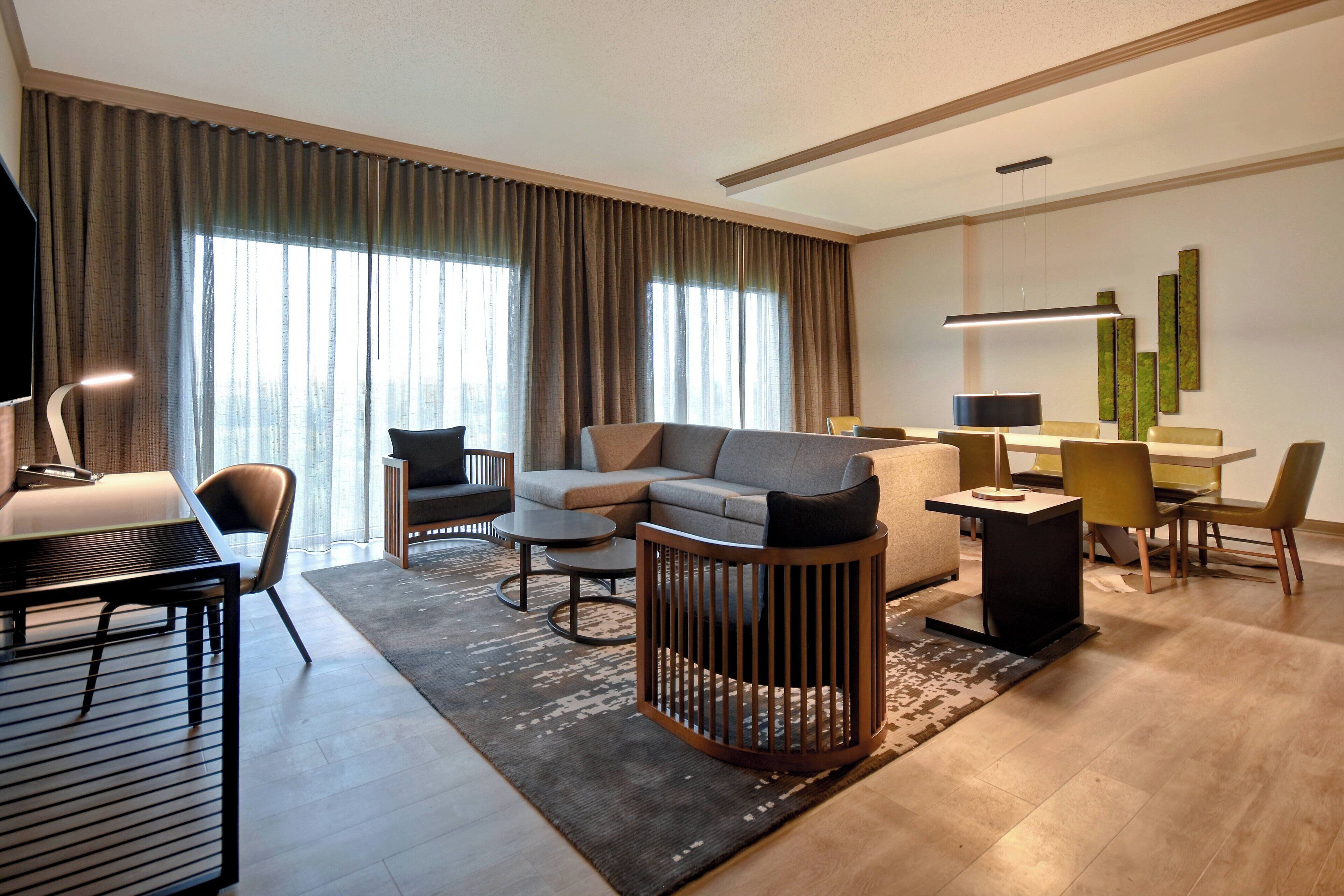 Une chambre d’hôtel moderne équipée d’un canapé, de fauteuils, d’une table à manger et d’un téléviseur.