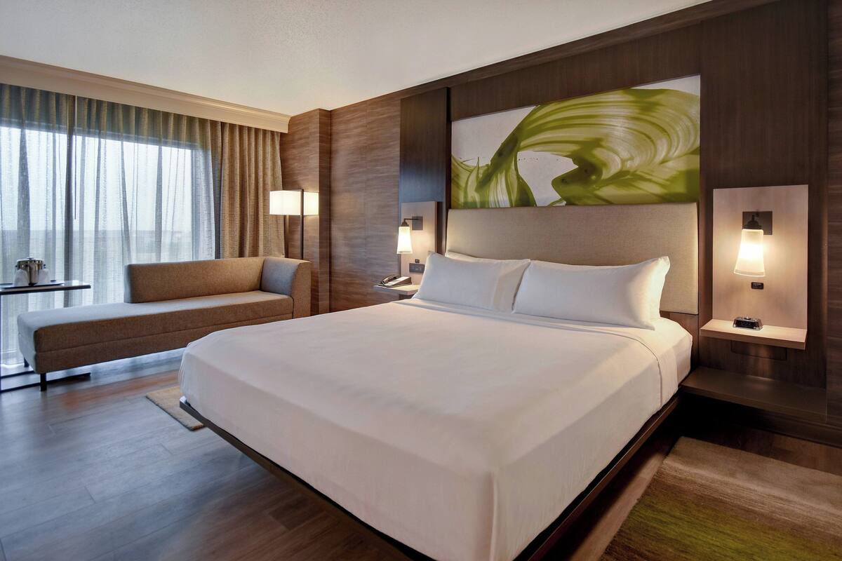 Ein modernes Hotelzimmer mit einem großen Bett, einer Schlafcouch und einem Schreibtisch.