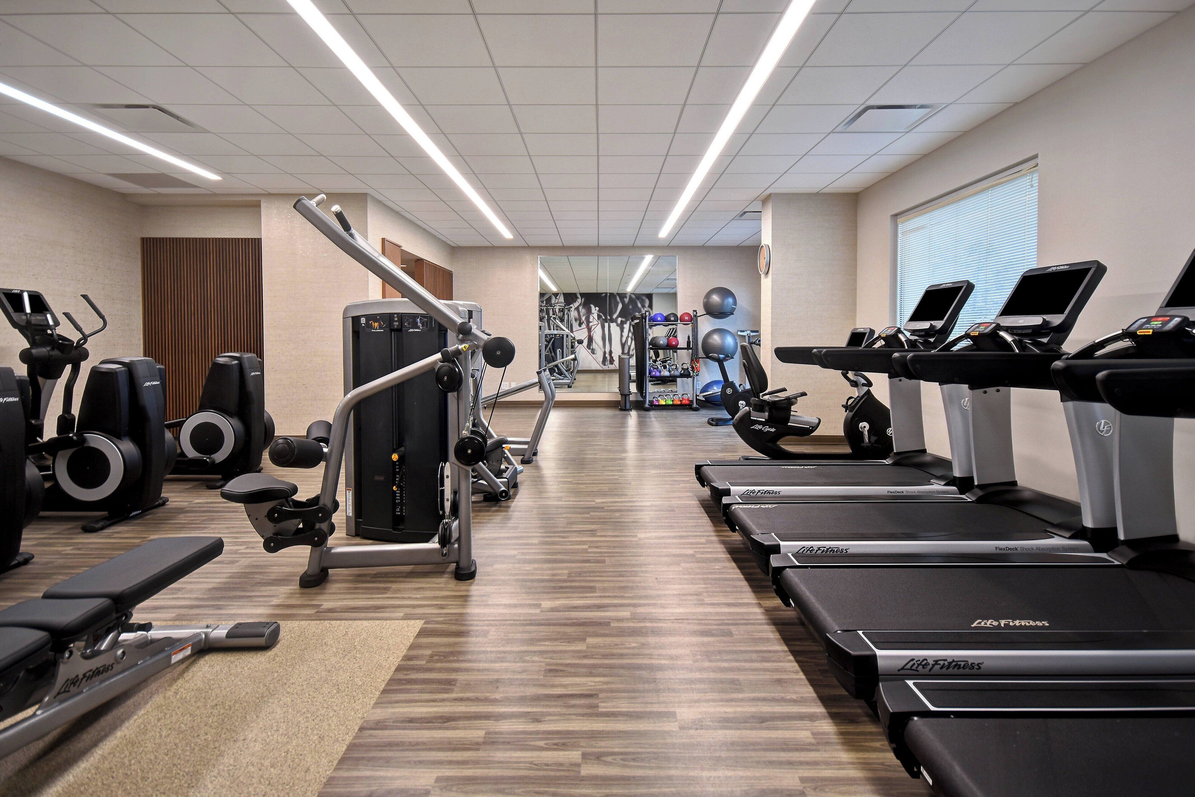 A gym with treadmills, elliptical machines, and weight equipment.