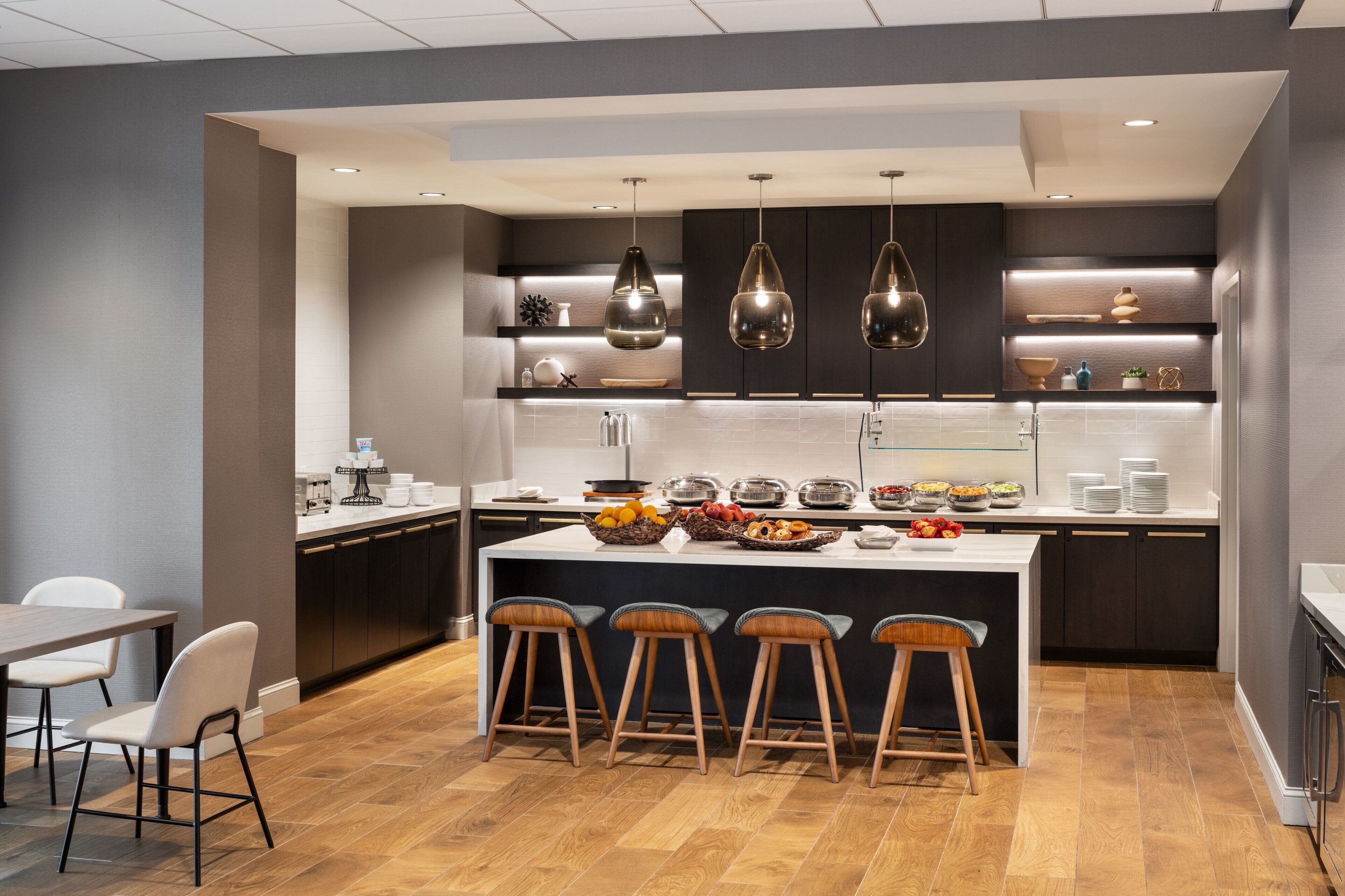 A modern kitchen with a central island, bar stools, and pendant lighting.