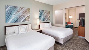 Une chambre d’hôtel avec deux lits, un bureau, une chaise et un téléviseur.