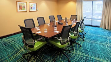 Un salón de conferencias con una mesa larga, sillas y suelo alfombrado.