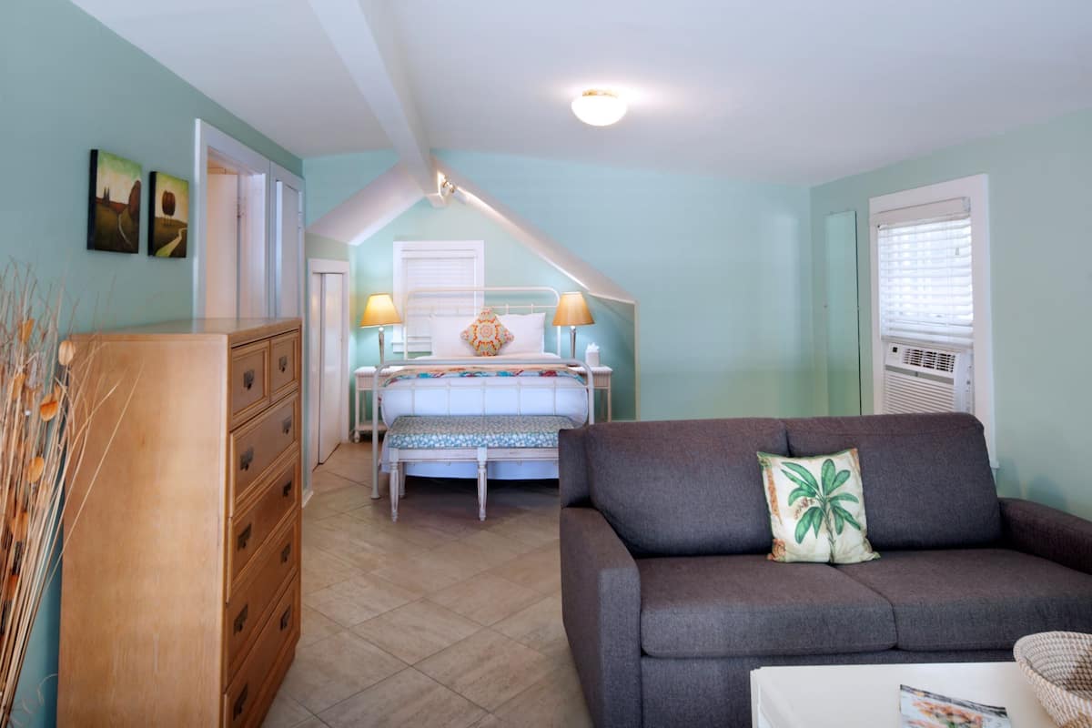 Un dormitorio con cama, lámparas de noche, cómoda y sofá.