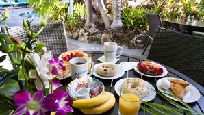 Una mesa de desayuno con diversos alimentos, como frutas, bollería y una taza de café.