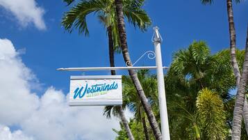 A sign with the text "Westinns" and "UNB I KEY WEST" against a backdrop of palm trees and a clear blue sky.