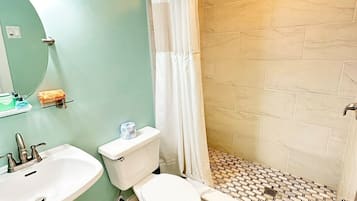Un baño con lavamanos, inodoro y ducha.