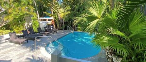 A pool area with lounge chairs and a small cabana.