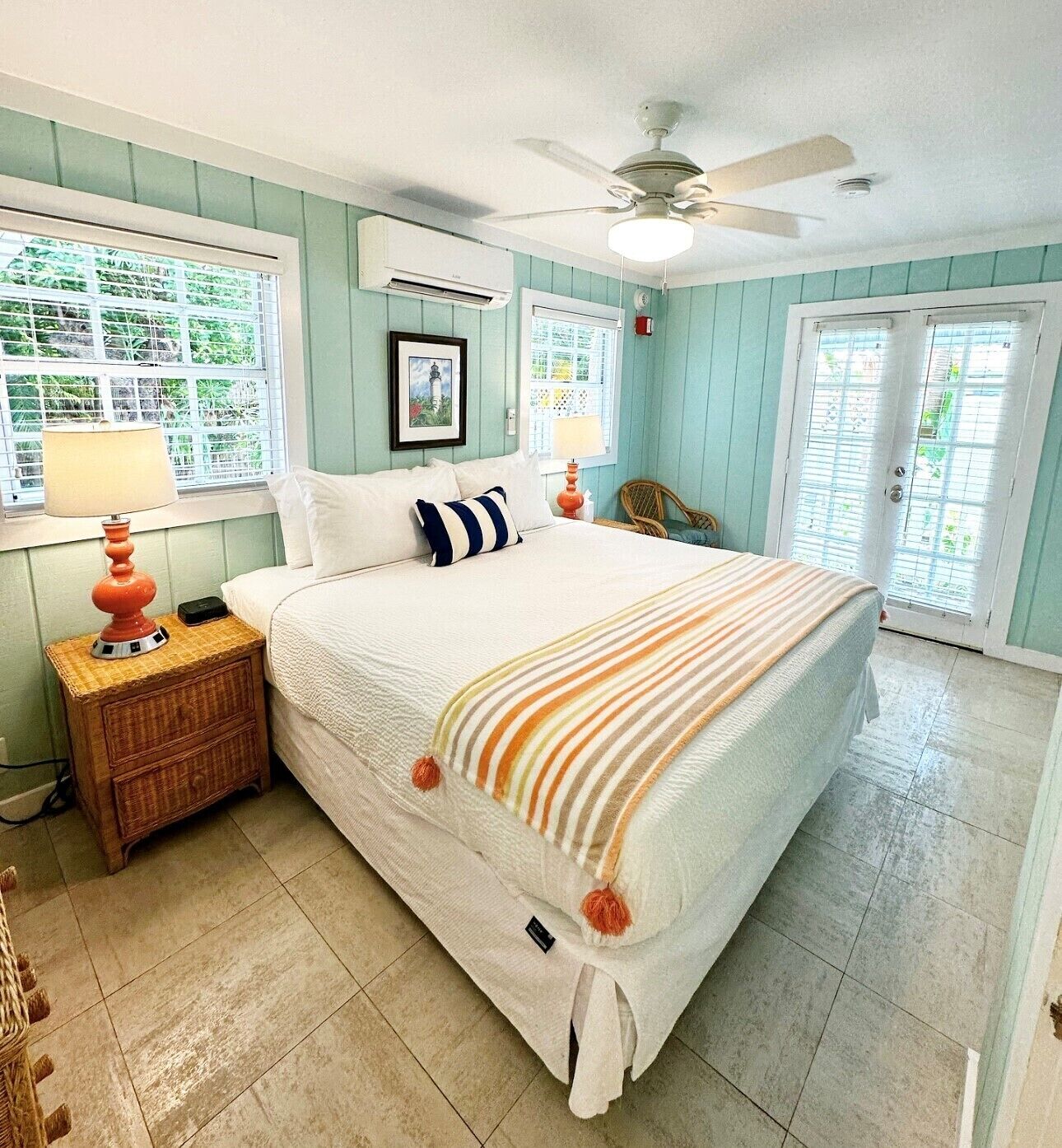 A bedroom with a bed, a nightstand, a chair, and a ceiling fan.
