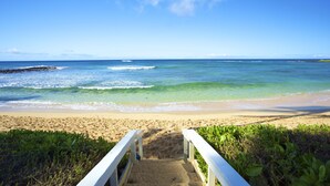 A beach with a wooden walkway leading to the shore.