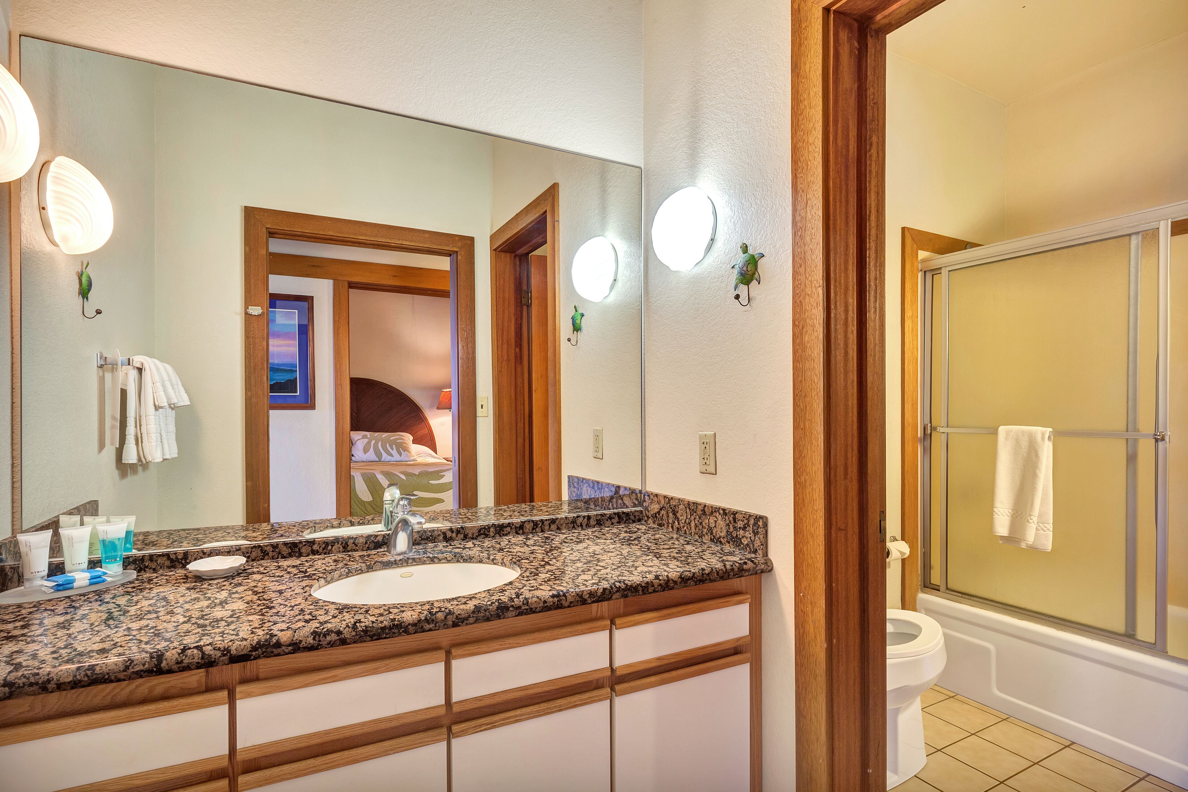 A bathroom with a granite countertop sink, a large mirror, and a shower enclosure.