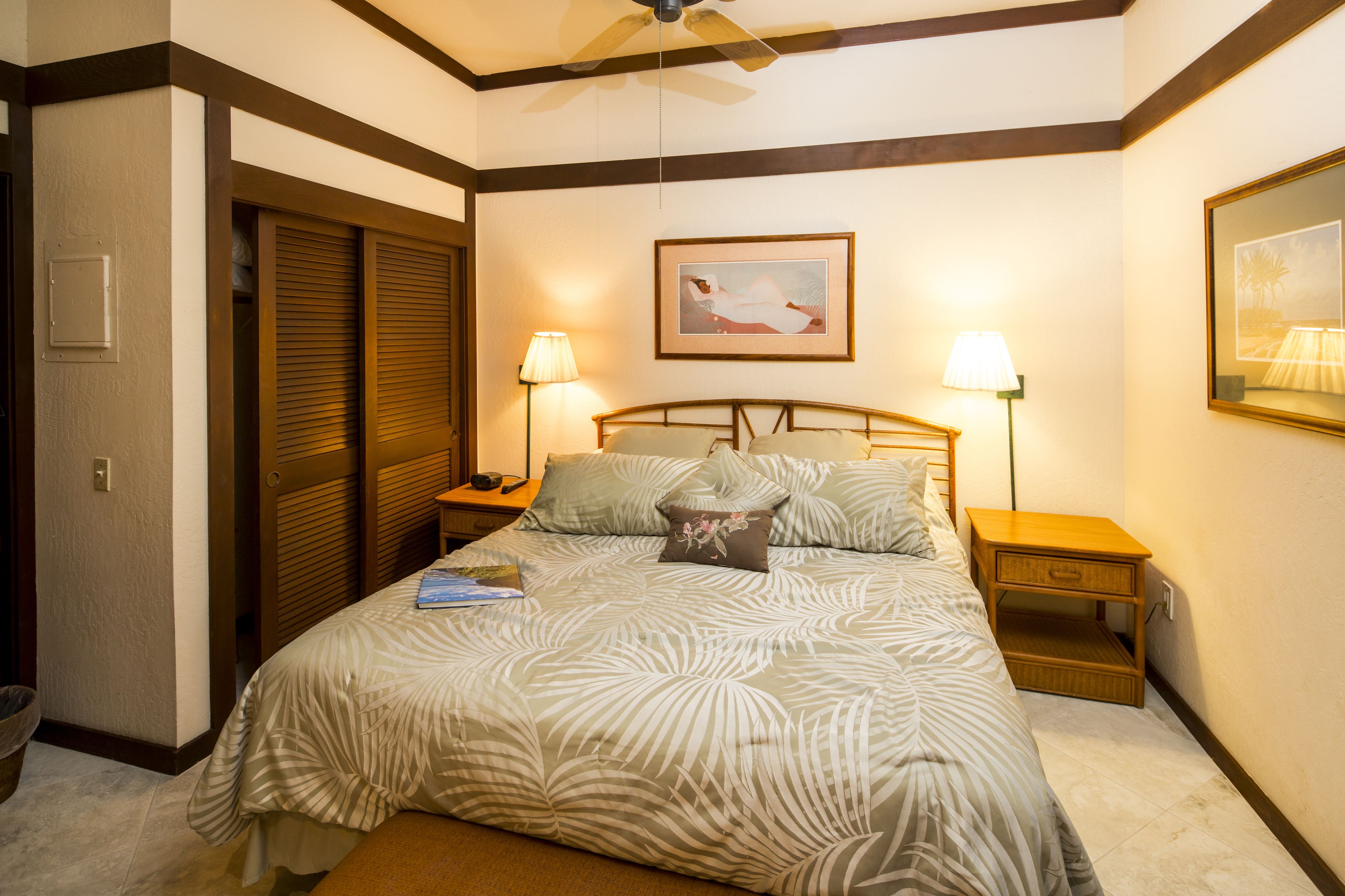 Un dormitorio con una cama, dos mesitas de noche, una lámpara de noche y un cuadro en la pared.