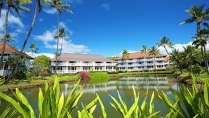 A hotel with a pool, surrounded by palm trees and greenery.