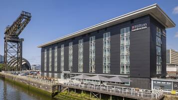 A modern building with a flat roof and large windows, labeled as a Hilton Garden Inn.