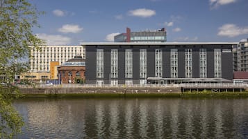 A modern building with a flat roof and large windows, located near a body of water.