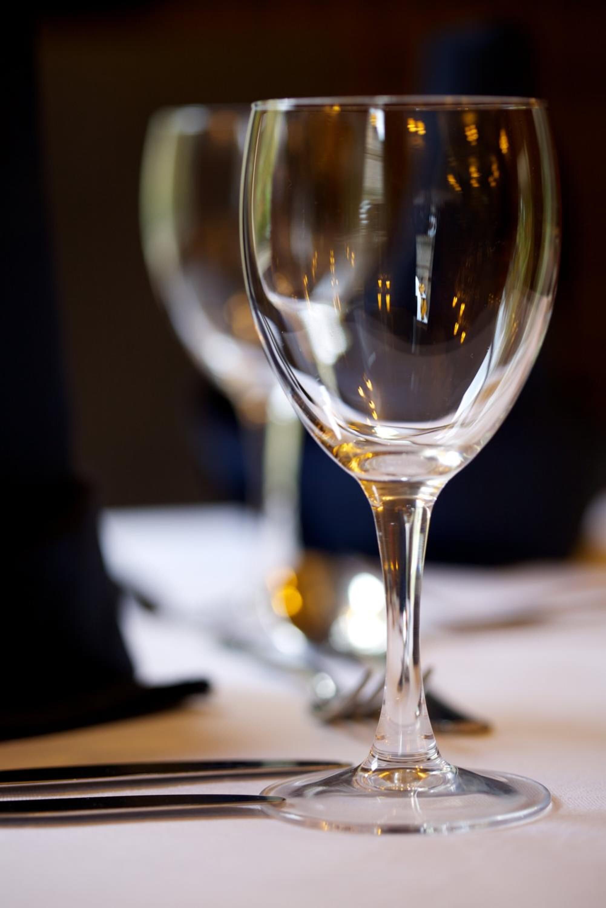 A clear glass wine glass on a table with a blurred background.