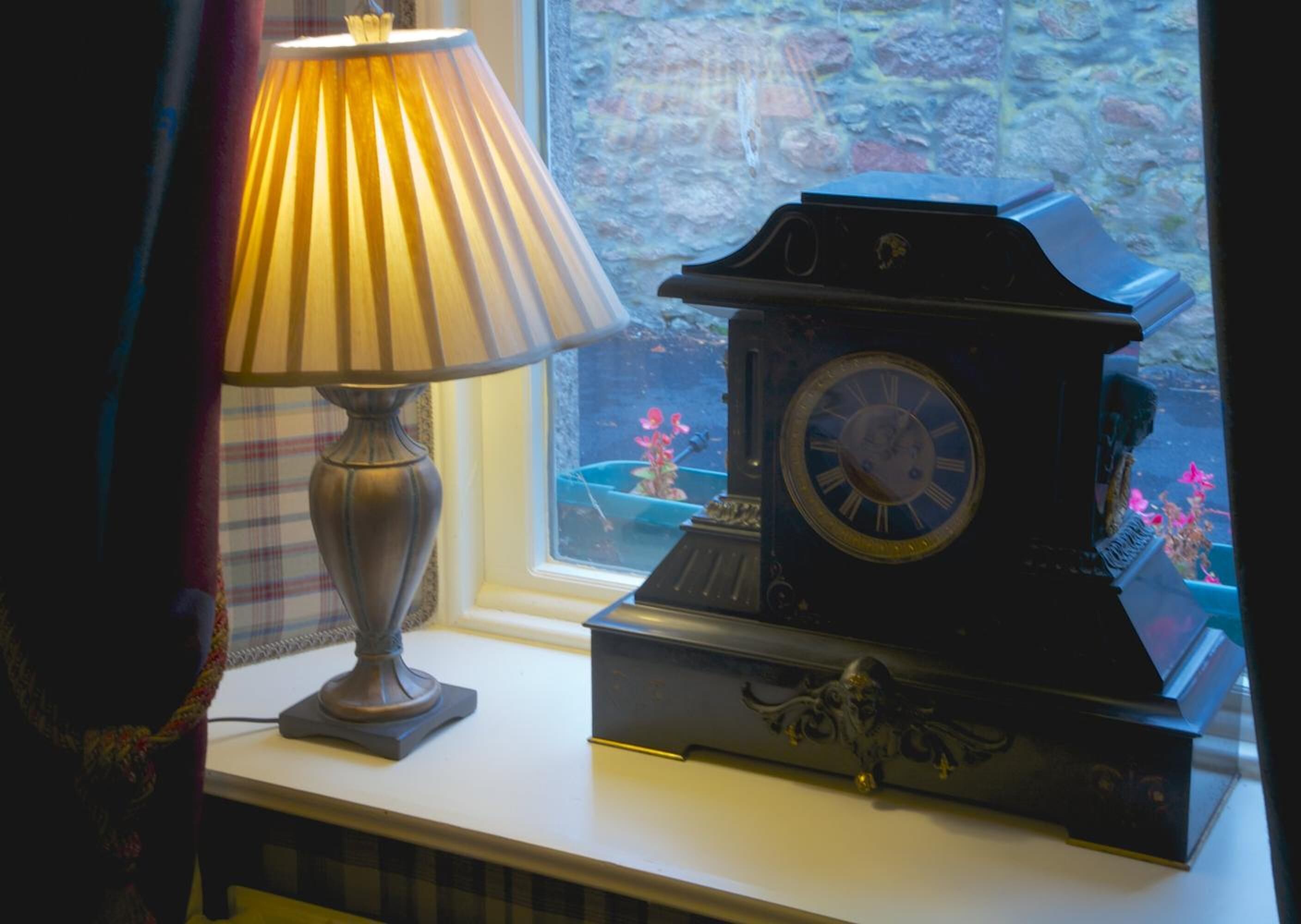 A table with a lamp and a grandfather clock.