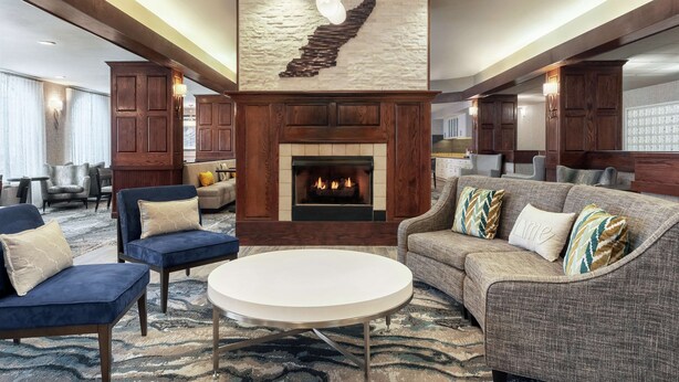 A spacious living area with a fireplace, comfortable seating, and a modern chandelier. - Homewood Suites by Hilton Erie (Erie)