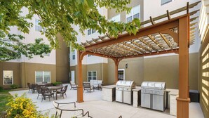 An outdoor patio with a pergola, seating, and a grill area. - Homewood Suites by Hilton Erie (Erie)