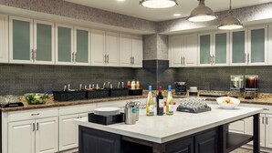A modern kitchen with white cabinets, a large island, and a patterned backsplash. - Homewood Suites by Hilton Erie (Erie)