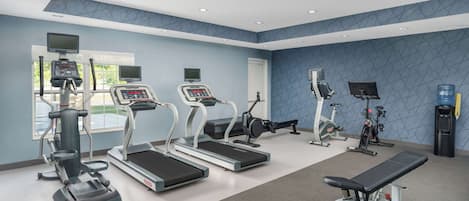 Un gimnasio con cintas de correr, una banca y diversos equipos de ejercicio.