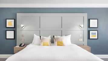 A hotel room with a large bed, two bedside tables, a phone, and artwork on the walls.