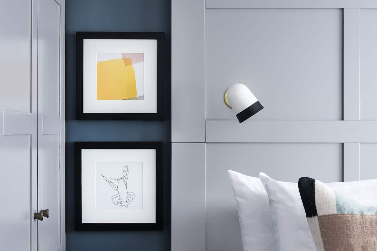A bedroom with a bed, a nightstand, and a wall-mounted lamp.