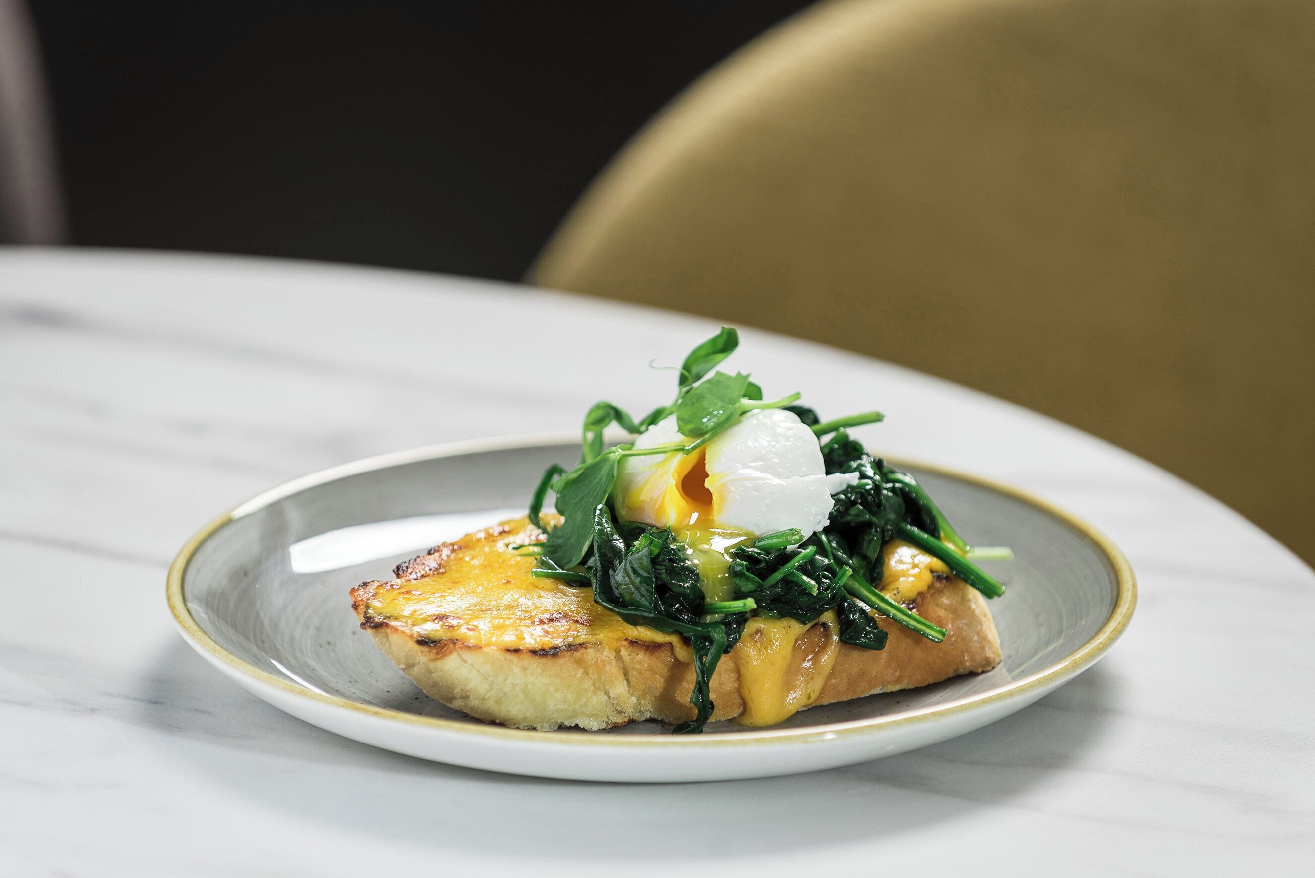 A plate with a poached egg, spinach, and a slice of toast on a white plate.