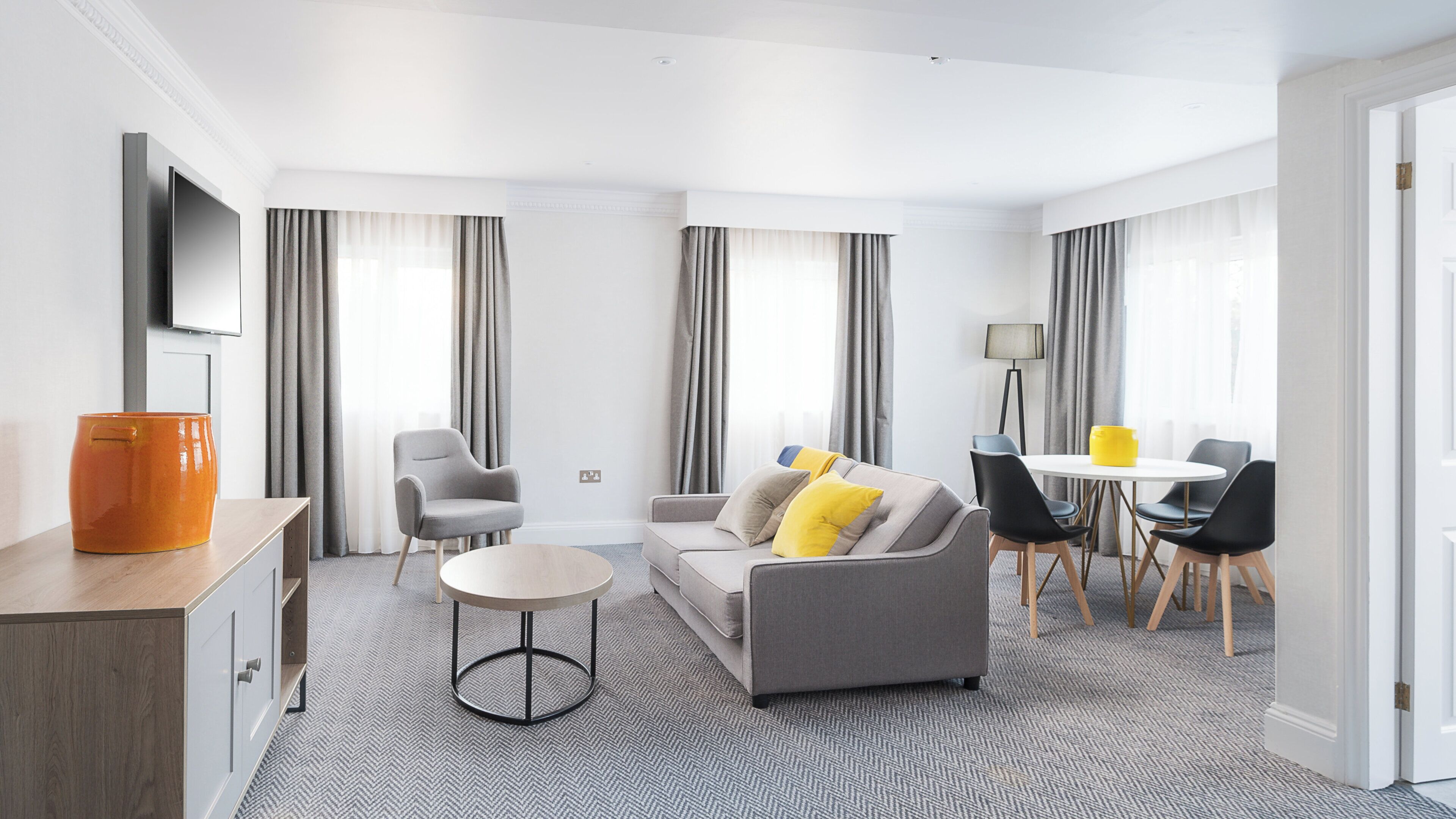 Una sala de estar moderna con un sofá, sillones, una mesa de centro y un comedor con mesa y sillas.