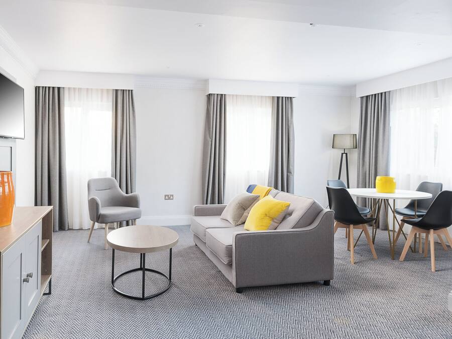 Una sala de estar moderna con un sofá, sillones, una mesa de centro y un comedor con mesa y sillas.