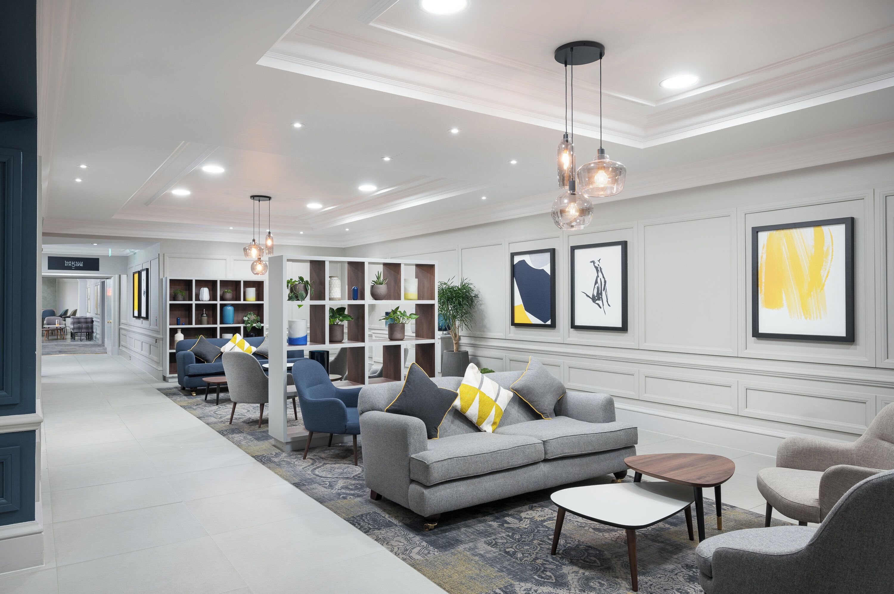 Una sala de estar moderna con un sofá gris, sillones, una mesa de centro y una estantería.