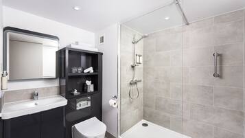 Een moderne badkamer met een douche, toilet, wastafel en een spiegel boven de wastafel.