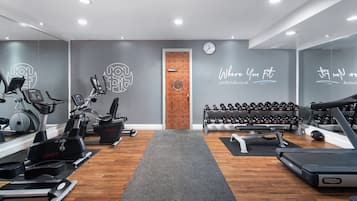 Un gimnasio con máquinas de cardio, pesas y una cinta de correr.