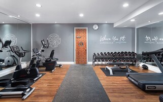 Un gimnasio con máquinas de cardio, pesas y una cinta de correr.