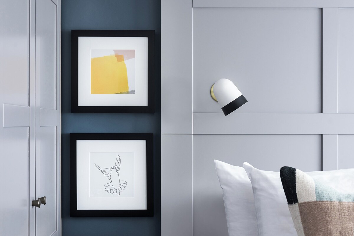 A bedroom with a bed, a nightstand, and a wall-mounted lamp.