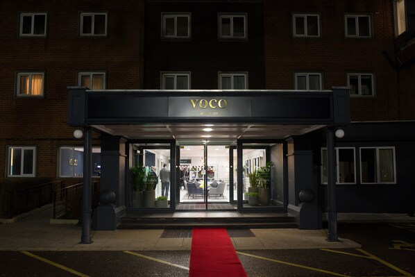 A hotel entrance with a red carpet, glass doors, and a sign reading "VOCO". - voco St. John's Solihull by IHG (Solihull)