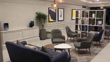 A modern lounge area with sofas, a coffee table, and a bookshelf with decorative items.