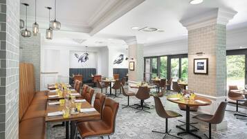 Ein Restaurant mit hohen Decken, Pendelleuchten und einer Mischung aus Tischen und Sitzbänken.