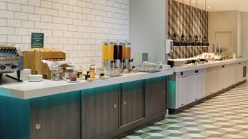 Una barra de buffet con una variedad de alimentos, una estación de café y dispensadores de bebidas.