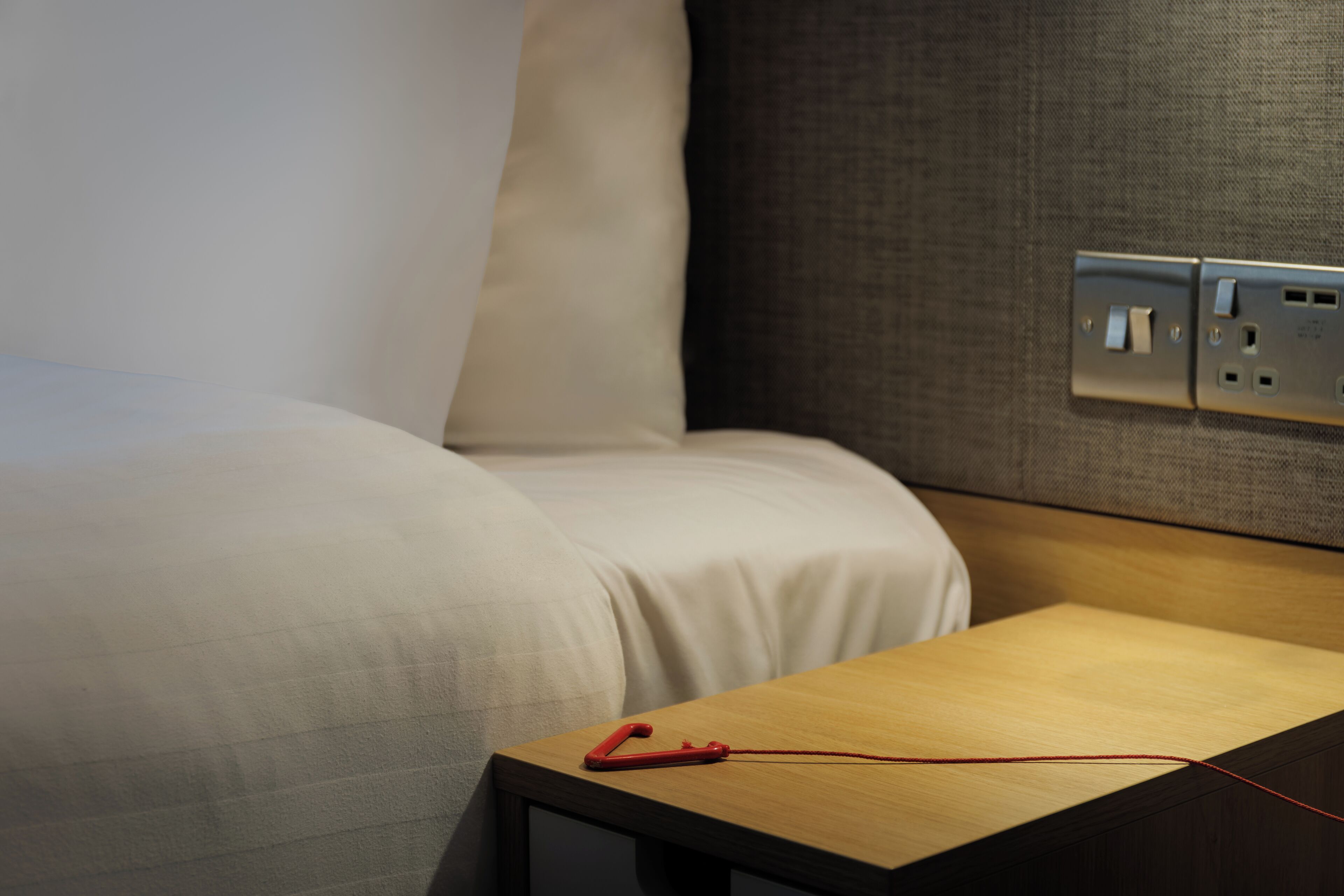 Una cama bien hecha con una mesita de noche de madera a su lado.
